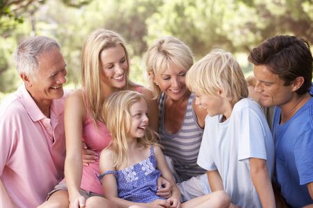 A family, with parents, children and grandparents, relaxing in a parkの写真素材
