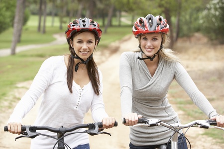 Two Female friends riding bikes in parkの写真素材