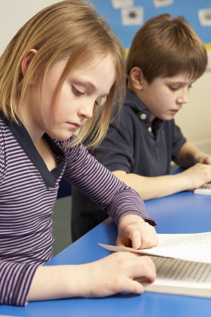 Schoolgirl Reading Book In Classroomの写真素材