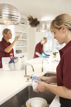 Team Of Commercial Cleaners Working In Domestic Kitchen