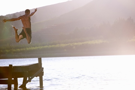 Young man jumping into lakeの写真素材