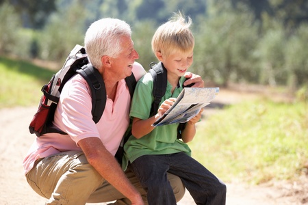 Senior man reading map with grandson on country walkの写真素材