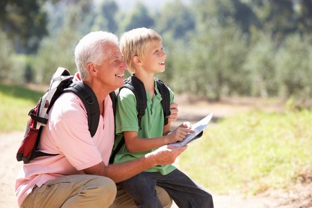 Senior man reading map with grandson on country walkの写真素材