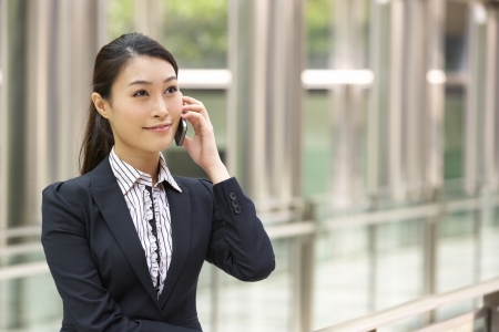 Chinese Businesswoman Outside Office On Mobile Phoneの写真素材