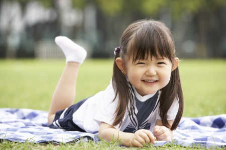 Young Chinese Girl Lying On Blanket In Parkの写真素材