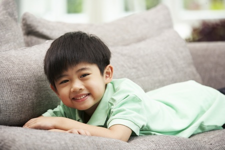 Young Chinese Boy Relaxing On Sofa At Homeの写真素材