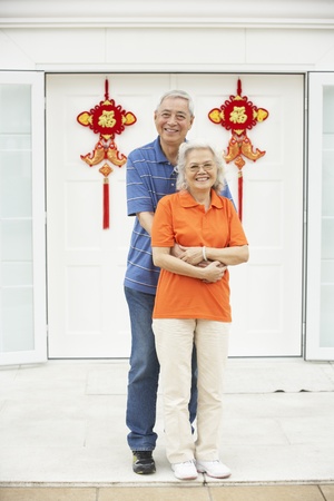 Senior Chinese Couple Outside Home Decorated With Welcoming Feng Shui Bannersの写真素材
