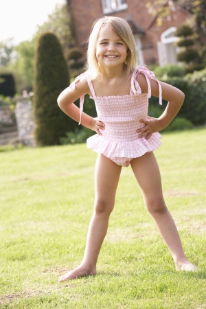 Portrait Of Young Girl Standing In Garden Wearing Swimming Costumeの写真素材