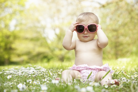 Baby Girl In Summer Dress Sitting In Field Wearing Sunglassesの写真素材