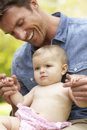 Father Sitting With Baby Girl In Field Of Summer Flowersの写真素材