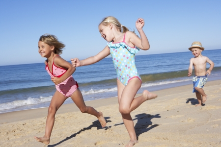 Three Children Running Along Beachの写真素材