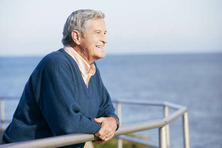 Senior Man Looking Over Railing At Sea