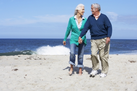Senior Couple Walking Along Beach Togetherの写真素材