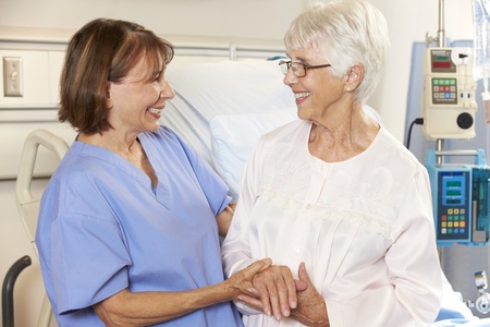 Nurse Talking To Senior Female Patient In Hospital Bedの写真素材