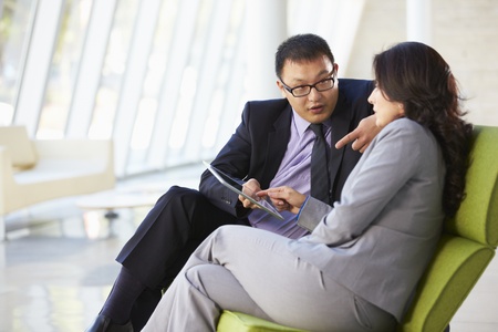 Businesspeople With Digital Tablet Sitting In Modern Officeの写真素材