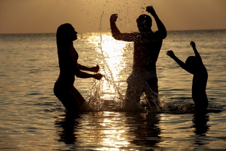 Silhouette Of Family Having Fun In Sea On Beach Holidayの写真素材