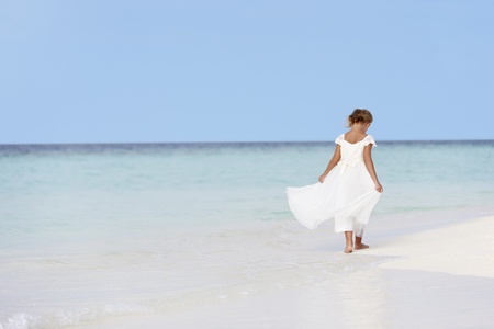 Young Girl In Bridesmaid Dress Walking On Beautiful Beachの写真素材