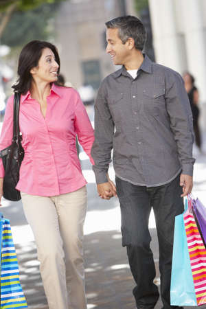 Couple Carrying Shopping Bags On City Streetの写真素材