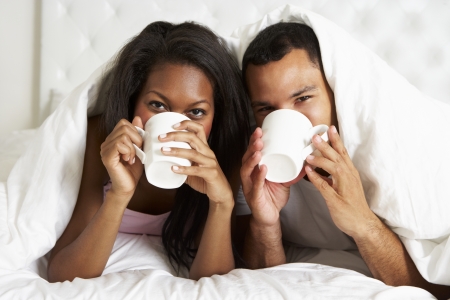 Couple Relaxing In Bed With Hot Drinkの写真素材