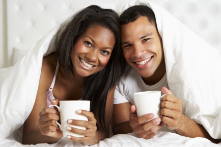 Couple Relaxing In Bed With Hot Drinkの写真素材