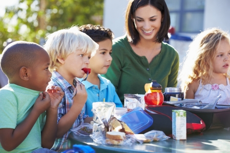 Elementary Pupils And Teacher Eating Lunchの写真素材