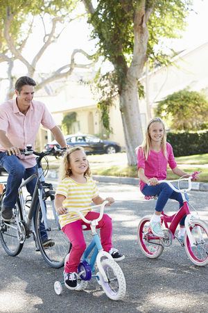 Family Cycling On Suburban Streetの写真素材