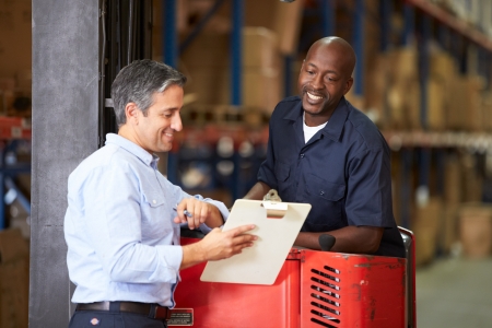 Fork Lift Truck Operator Talking To Manager In Warehouseの写真素材