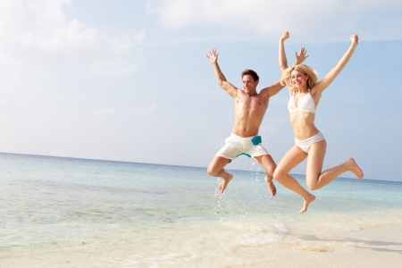 Couple Jumping In The Air On Tropical Beachの写真素材