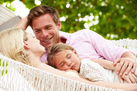 Family Relaxing In Beach Hammock With Sleeping Daughterの写真素材