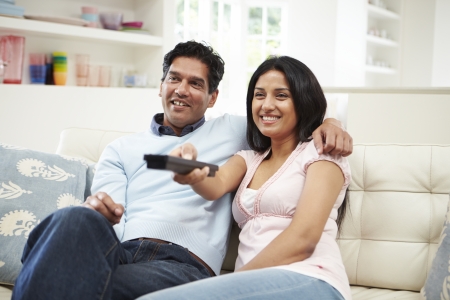 Indian Couple Sitting On Sofa Watching TV Togetherの写真素材