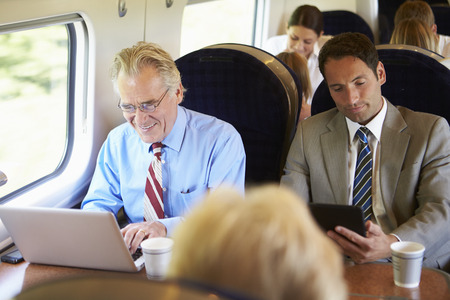 Businessman Commuting To Work On Train And Using Laptop