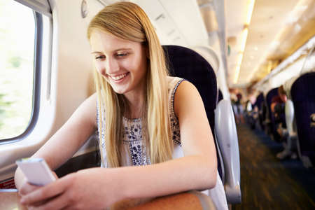 Teenage Girl Using Mobile Phone On Train Journey