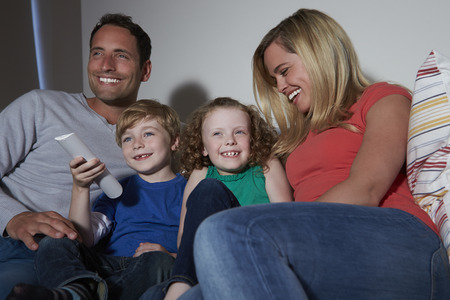 Family Sitting On Sofa Watching TV Togetherの写真素材