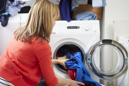 Woman Loading Clothes Into Washing Machineの写真素材