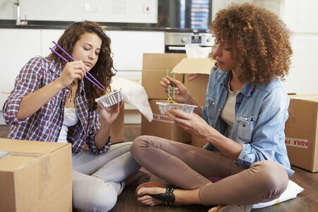 Two Women Moving Into New Home Enjoying Takeaway Mealの写真素材