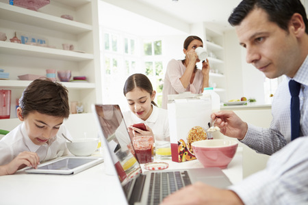 Family Using Digital Devices At Breakfast Tableの写真素材