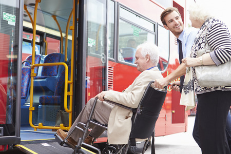 Driver Helping Senior Couple Board Bus Via Wheelchair Rampの写真素材