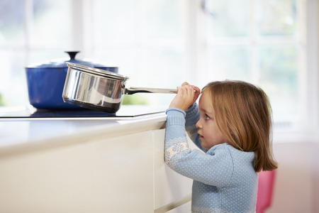 Young Girl Risking Accident With Pan In Kitchenの写真素材