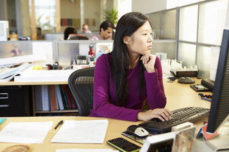 Asian Woman Working At Computer In Modern Officeの写真素材