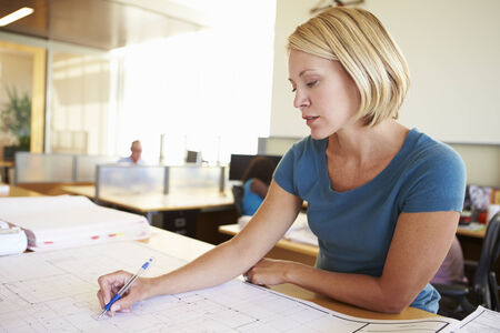 Female Architect Studying Plans In Officeの写真素材