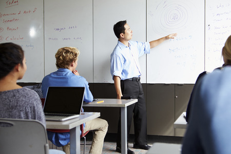 Tutor With High School Students In Class Using Laptops