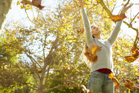 Woman Throwing Autumn Leaves In The Air