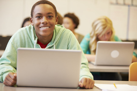 Male High School Student At Desk In Class Using Laptopの写真素材