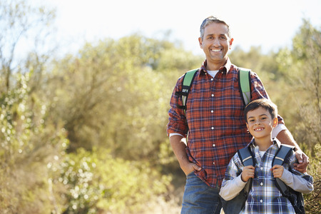 Father And Son Hiking In Countryside Wearing Backpacksの写真素材