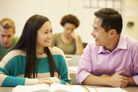 Female High School Student With Teacher Studying At Deskの写真素材