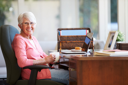 Senior Woman Using Laptop On Desk At Homeの写真素材