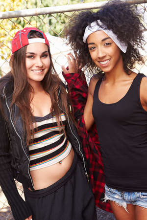 Two Young Women In Urban Setting Standing By Fenceの写真素材