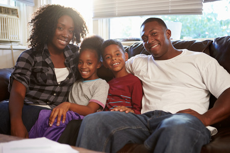 Portrait Of Happy Family Sitting On Sofa Togetherの写真素材