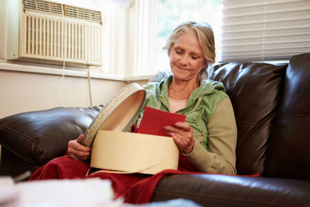 Senior Woman Keeping Warm Under Blanket With Memory Box