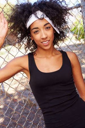 Portrait Of Young Woman In Urban Setting Standing By Fenceの写真素材